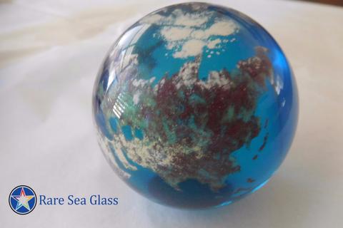 Teal-colored world globe paperweight from Lundberg Studios with visible continent patterns