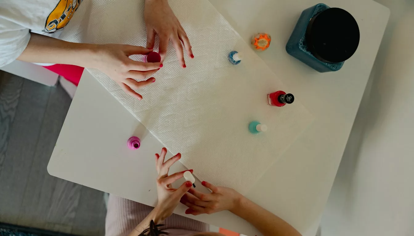 Two children working together on a craft project at a table, creating art with natural materials