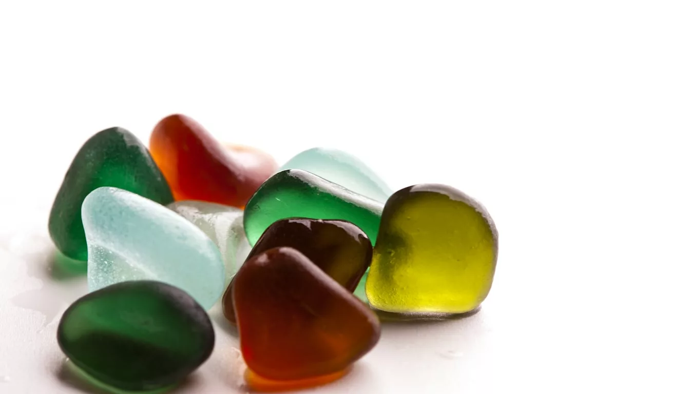 Colorful frosted sea glass pieces in shades of green, blue, white, and amber arranged for a craft project